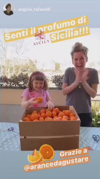 Mamma e figlia annusano le arance appena arrivate